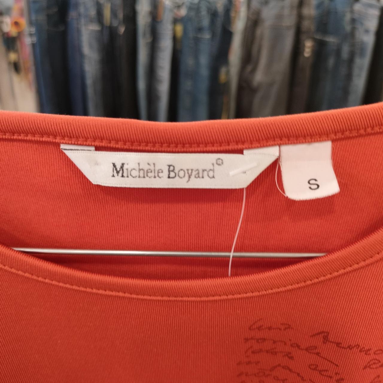 Red garment with a Michele Boyard label in a clothing store setting