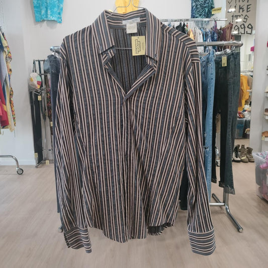Striped shirt on a hanger in a store setting with clothing racks and shelves in the background