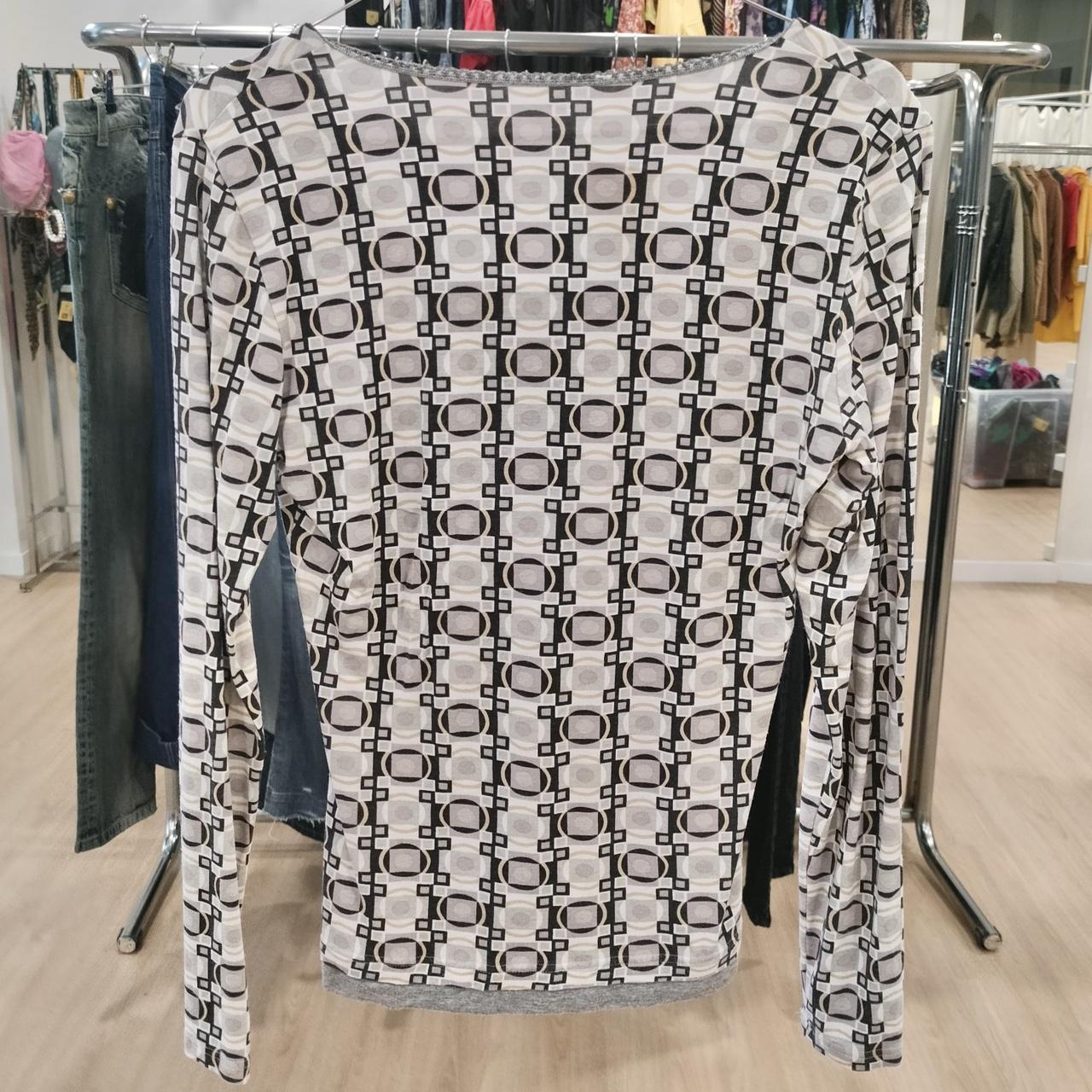 Long sleeve shirt with geometric square and circle pattern, hanging in a second hand shop