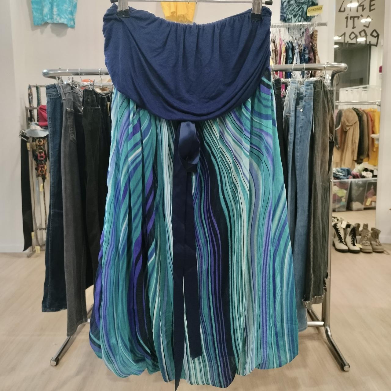Blue and teal pleated midi skirt with striped pattern hanging in a sustainable fashion store