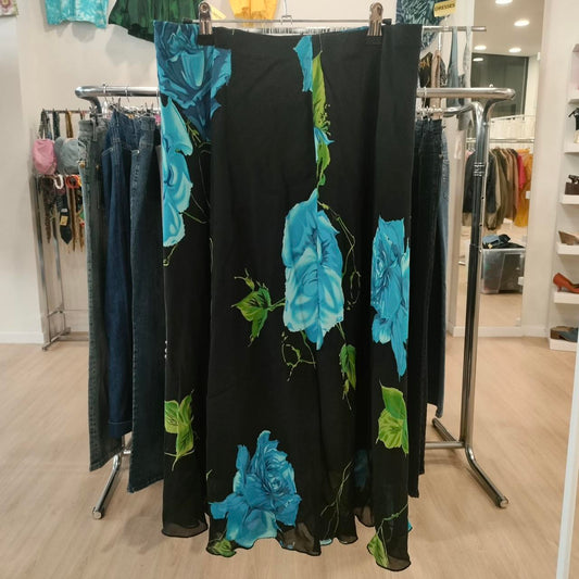 Black maxi skirt with large blue floral print, hanging in a second hand clothing store