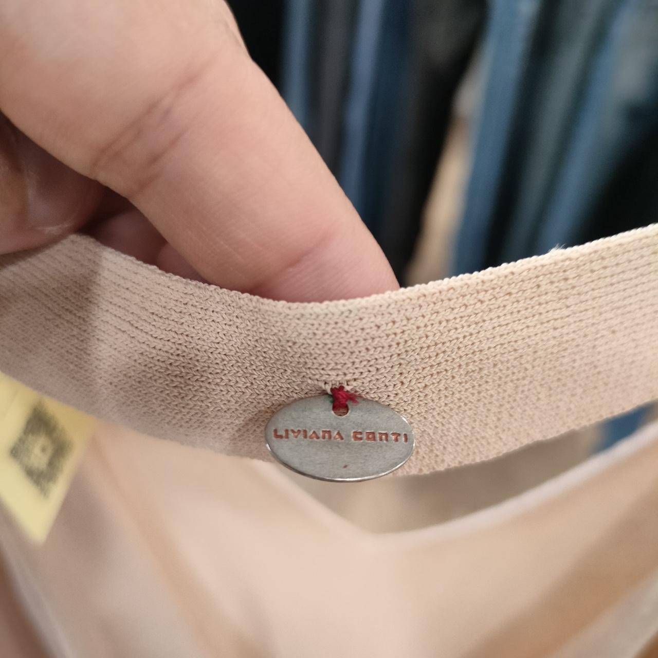 Close-up of a beige fabric item with a brand label, held by a hand