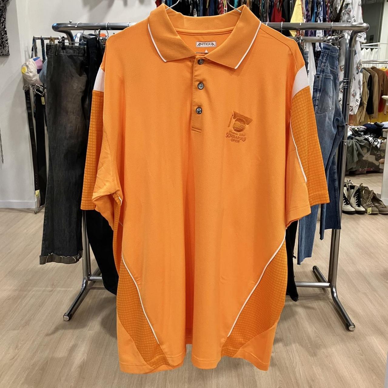 Orange polo shirt with white accents on a rack in a store setting