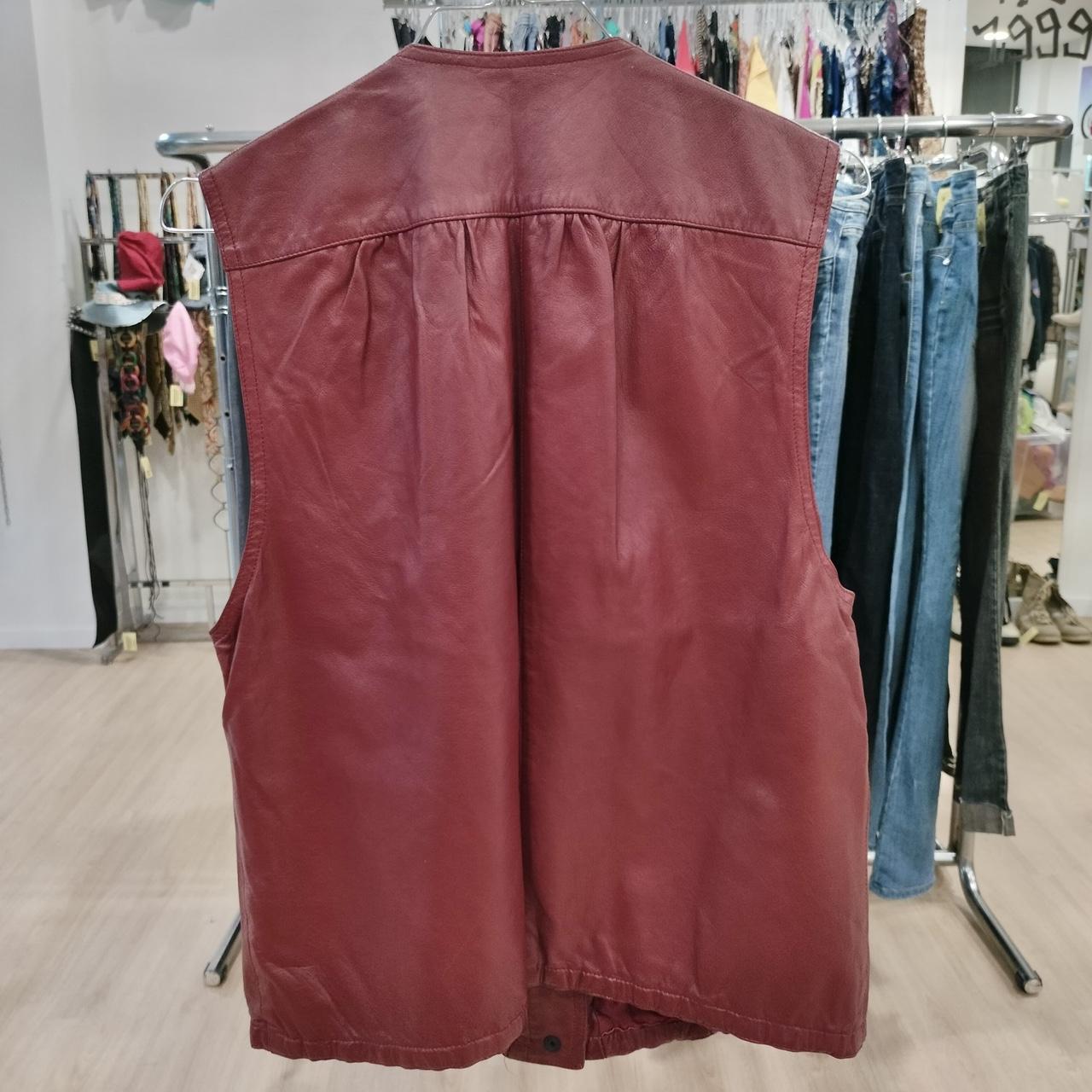 Maroon leather vest on a rack in a store setting