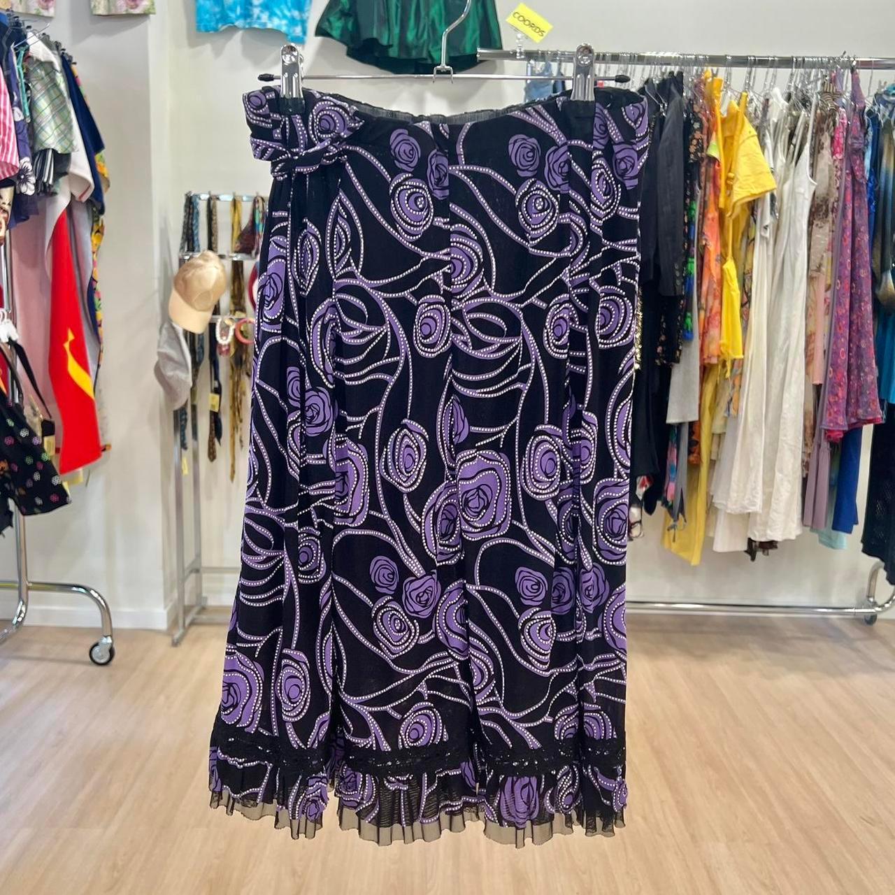 Purple floral patterned skirt with black mesh hem displayed in a vintage clothing store