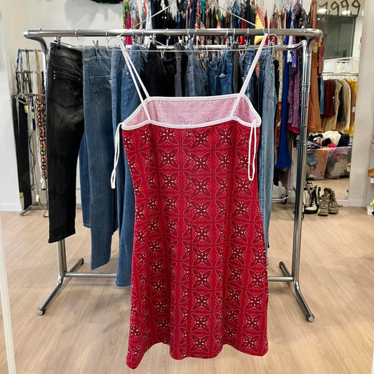 Red patterned dress hanging on a rack with jeans in a store setting