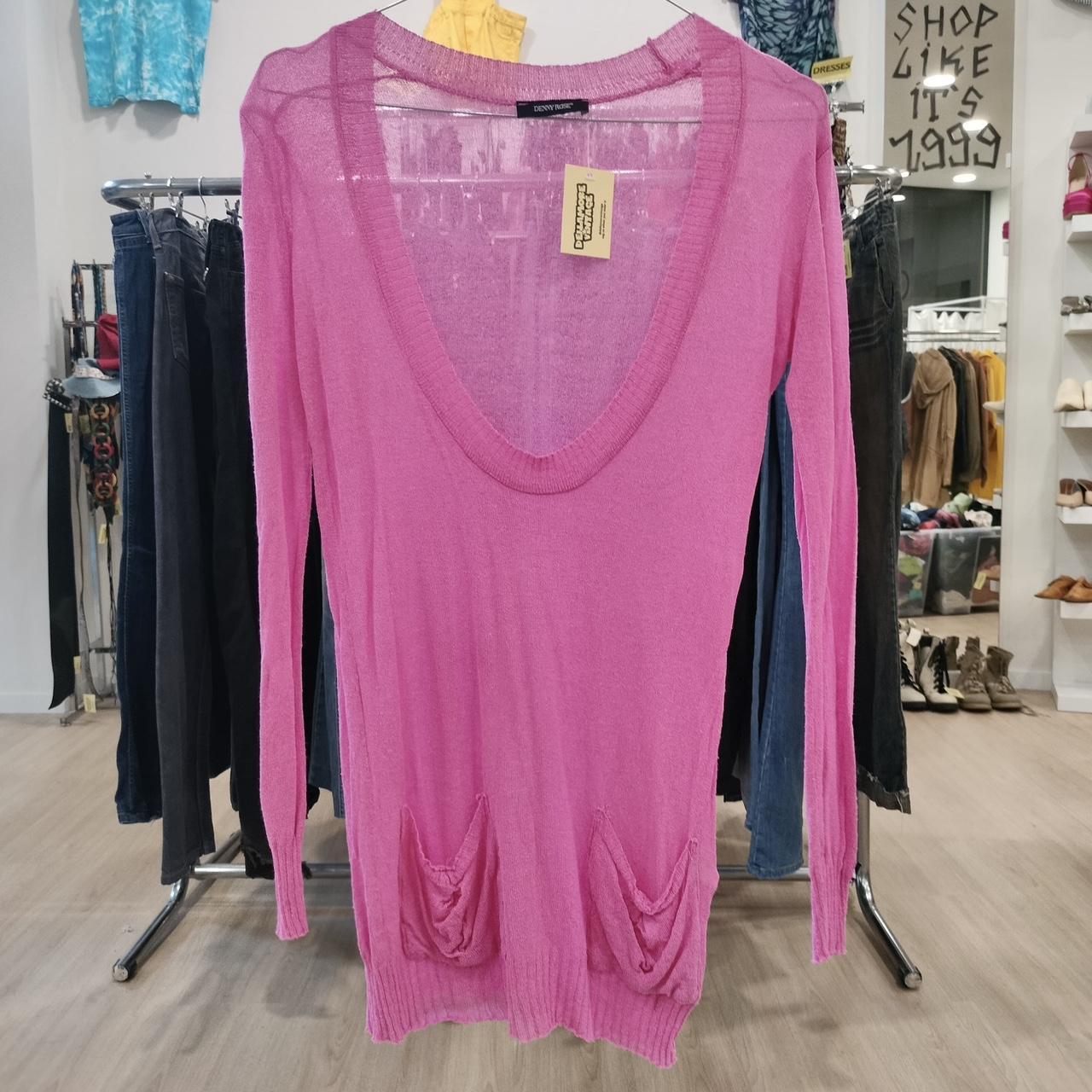 Pink long-sleeve top with a tag on a rack in a store setting