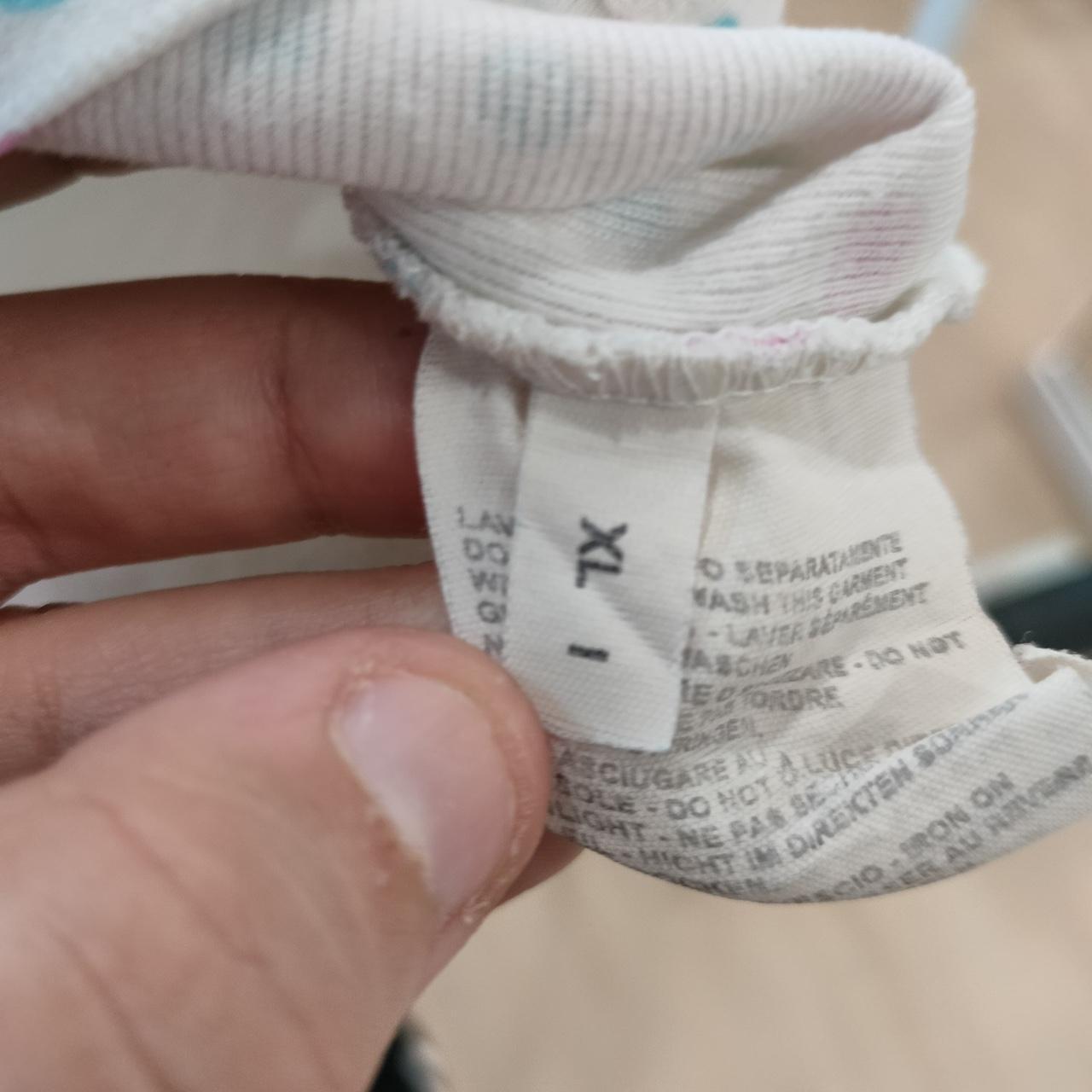 Close-up of a hand holding a white garment care label showing size XL and washing instructions