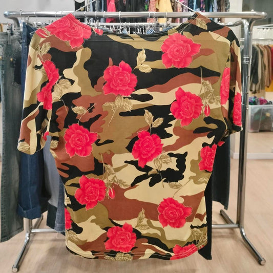 Short sleeve shirt with camouflage and red rose floral print, hanging in a clothing store