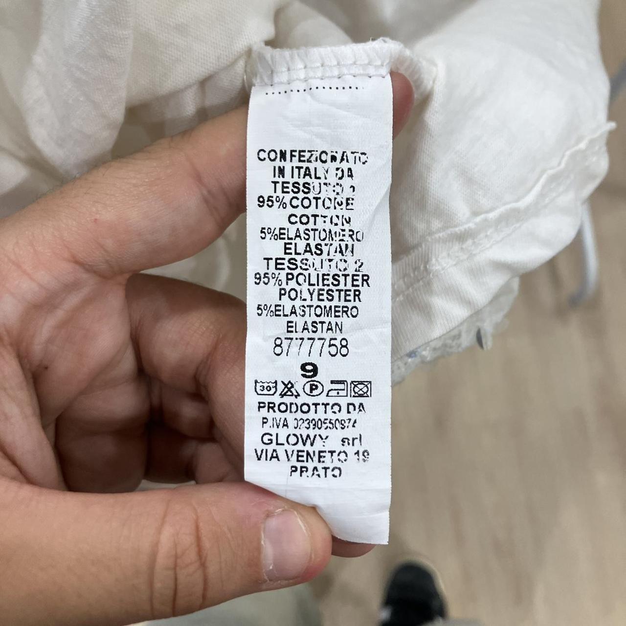 Clothing label showing fabric composition of cotton, polyester, and elastane with care symbols.