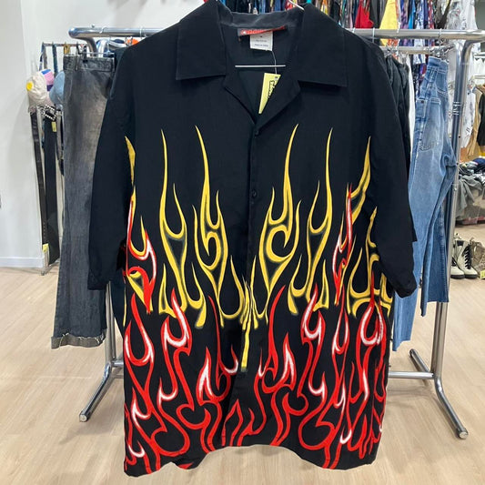 Black shirt with red and yellow flame design on a clothing rack
