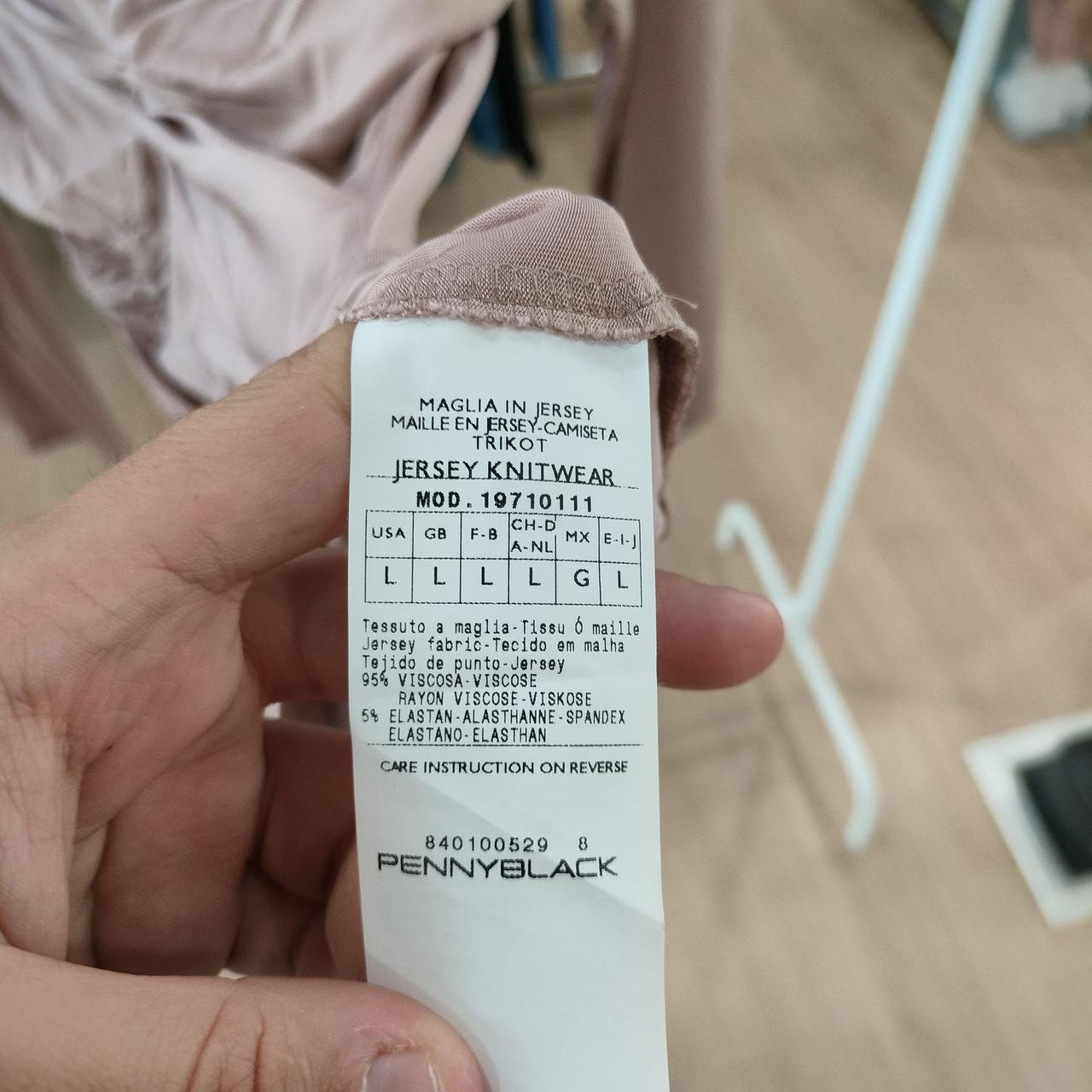 Close-up of a clothing label held by a hand, with a blurred background