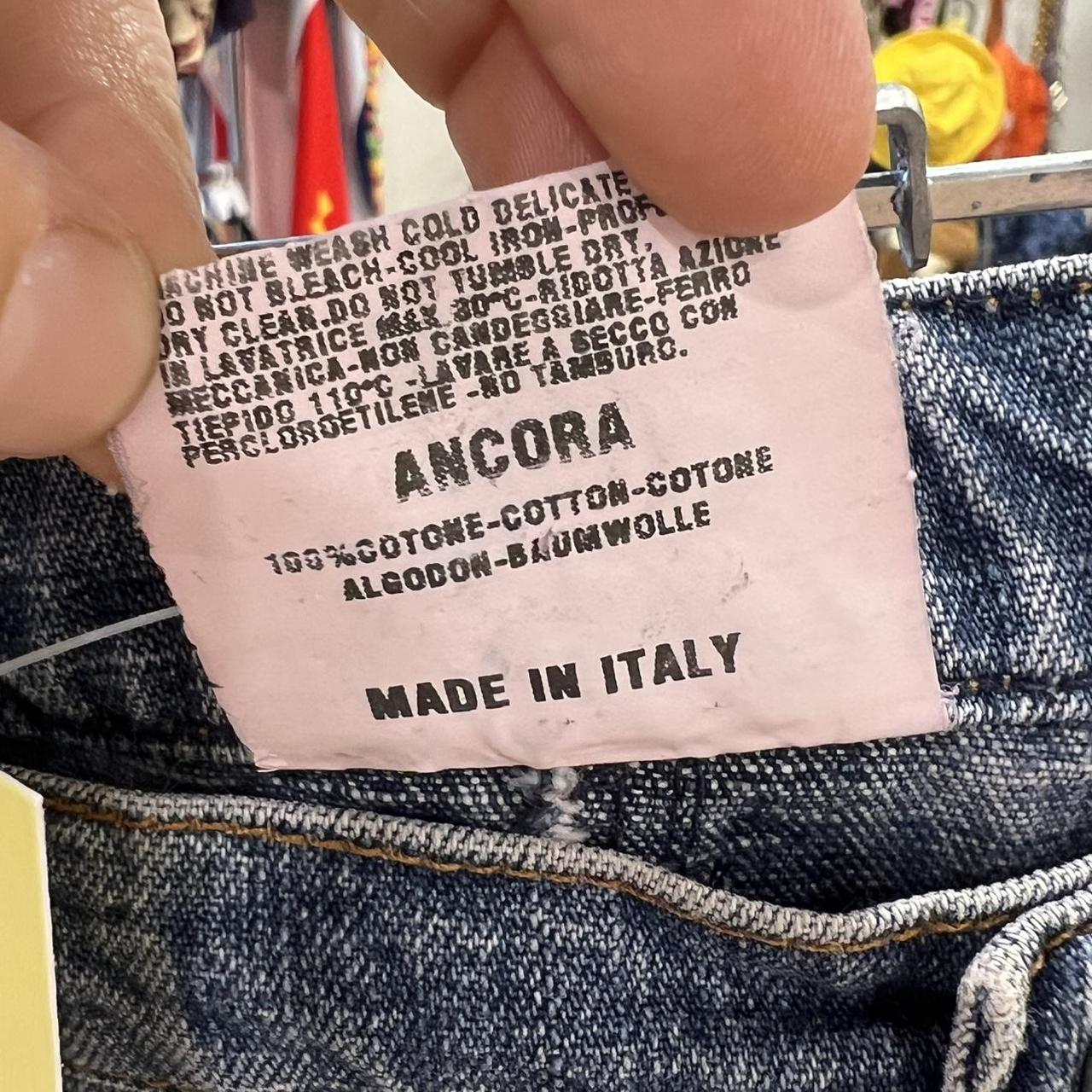 Close-up of a clothing label on denim fabric with 'Ancora' branding and text