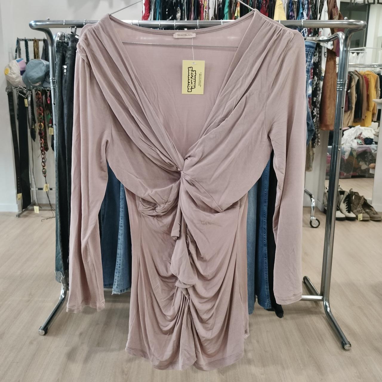 Pink draped dress on a rack with a tag in a store setting