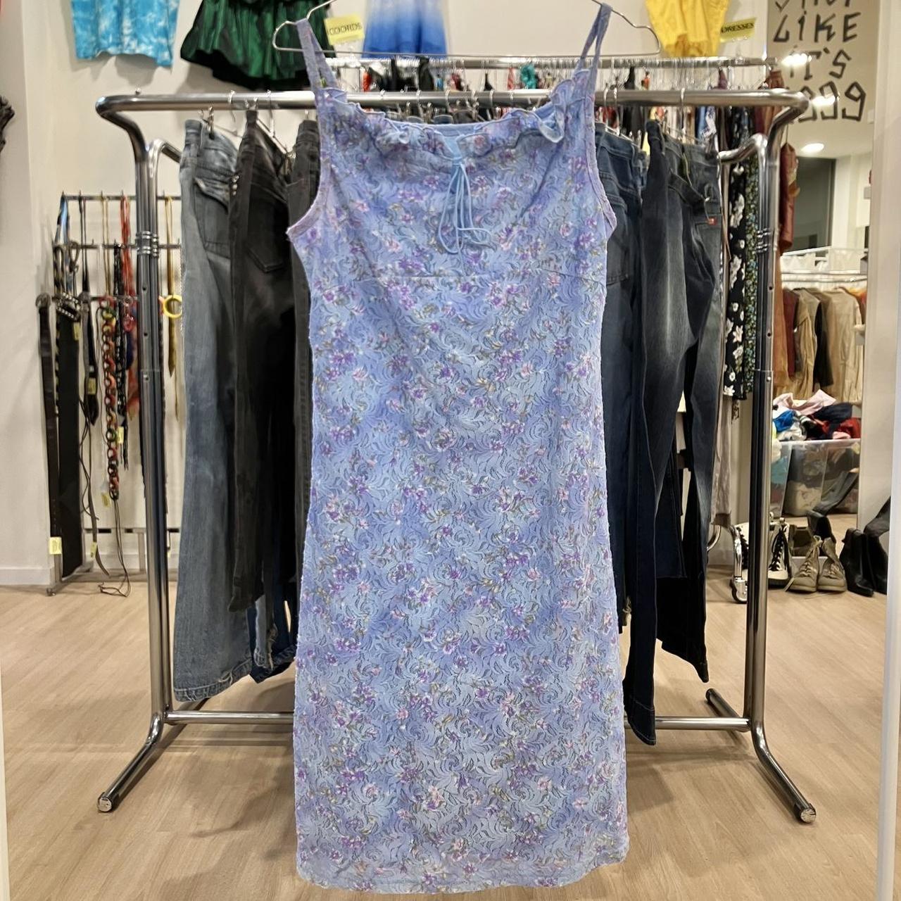 Light purple floral lace slip dress hanging in a second hand fashion store