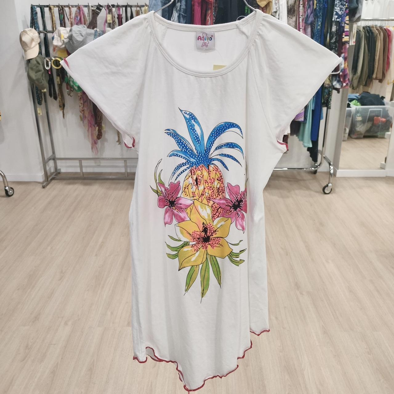 White dress with pineapple and tropical flower print, displayed in a clothing store.