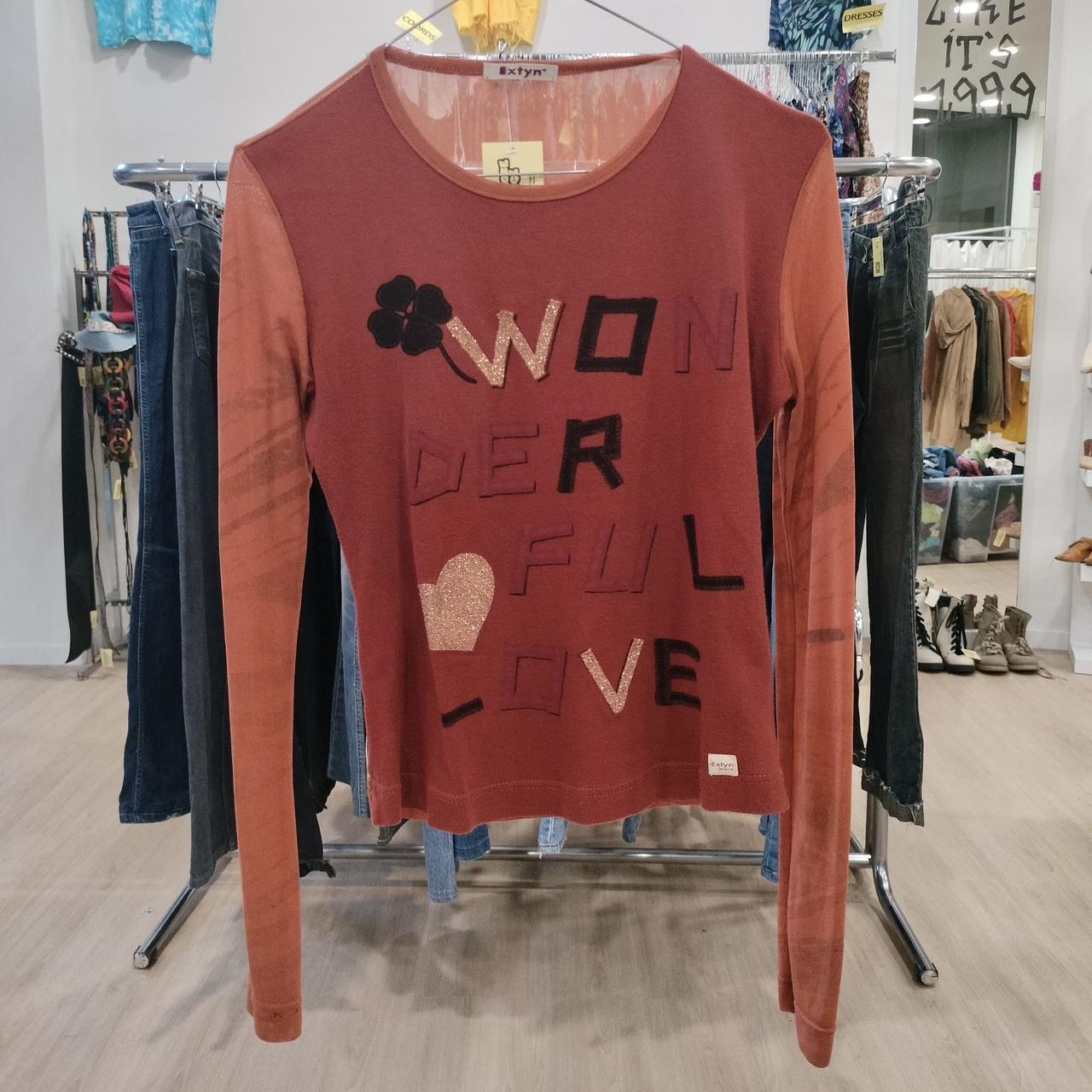 Red sweater with 'Wonderful Love' text on a rack in a store setting
