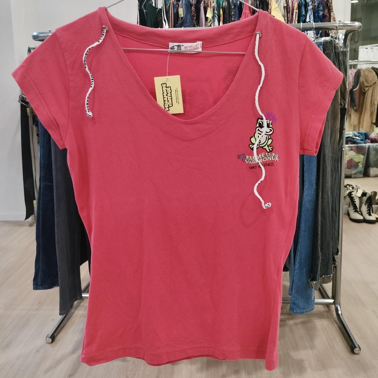 Pink t-shirt with a small graphic on a hanger in a store setting