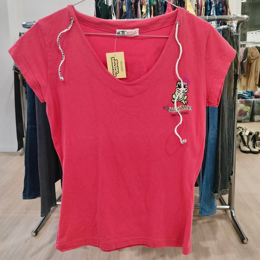 Pink t-shirt with a small graphic on a hanger in a store setting