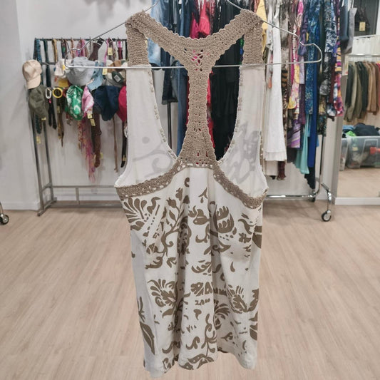 Beige and white crochet racerback tank top with floral pattern, hanging in a second hand fashion store