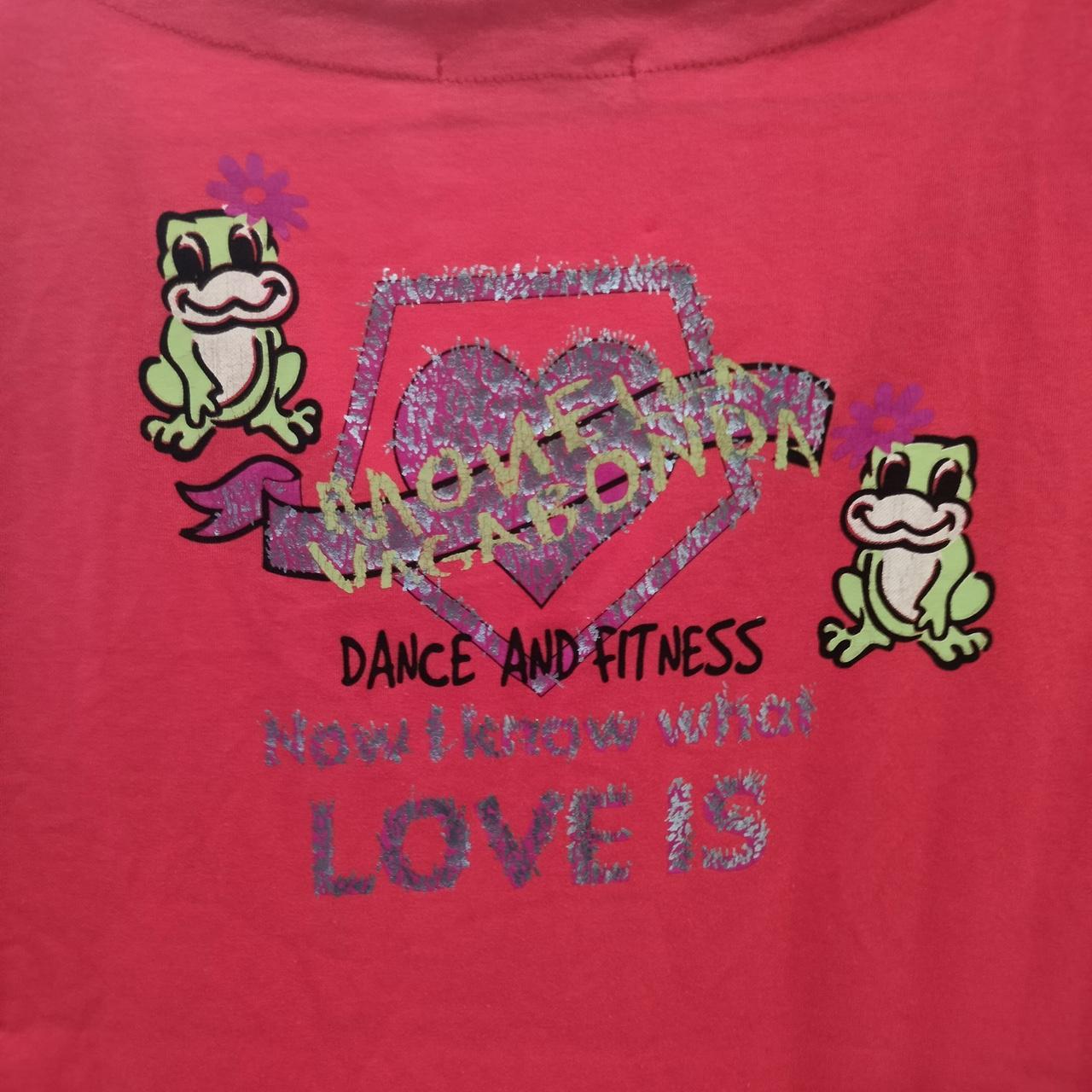 Red shirt with frog graphics and text on a pink background