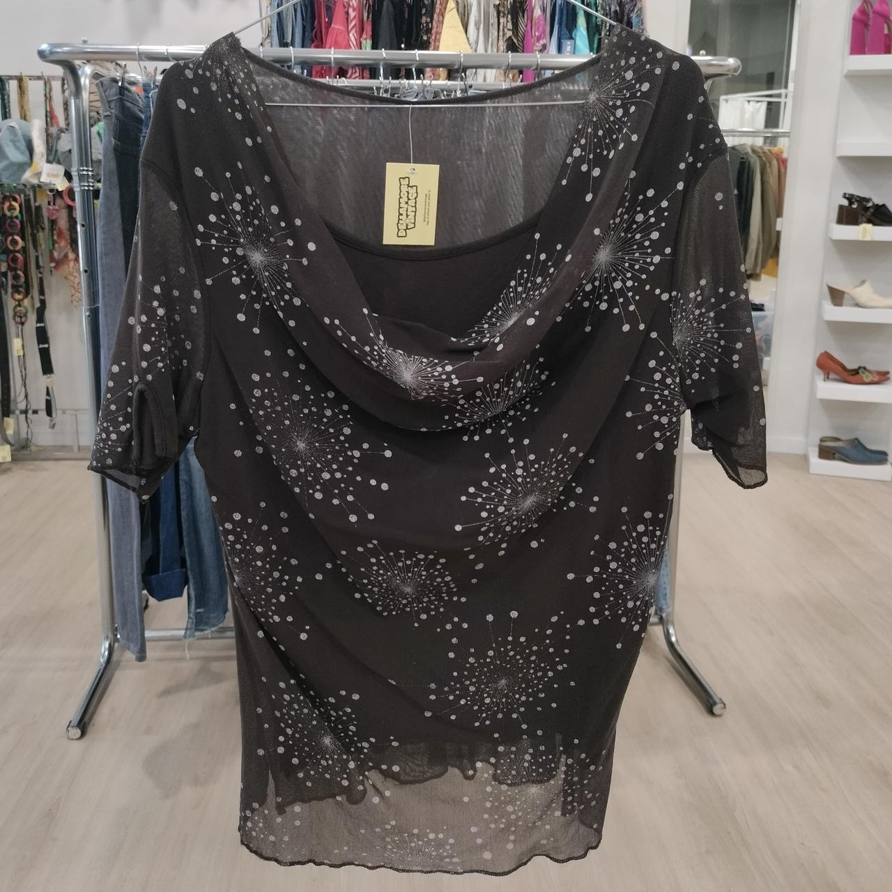 Black sheer top with white dandelion print and cowl neckline, displayed in boutique