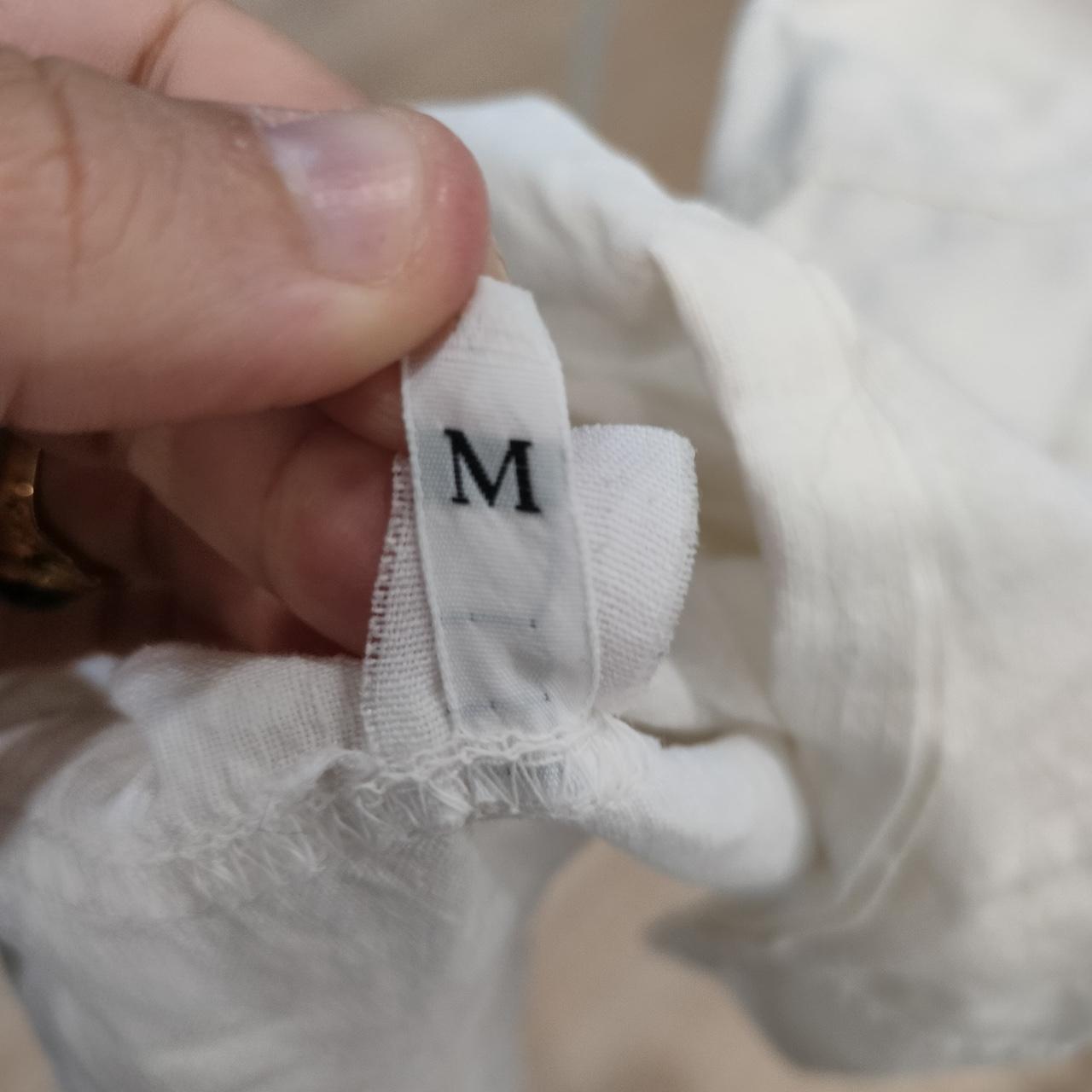 Close-up of a white fabric clothing tag showing size M, sustainable fashion focus
